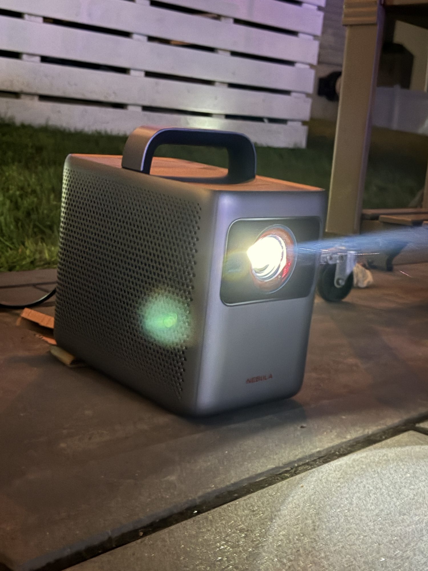 The Light Haus 4K projector on a patio at night with its beam visible