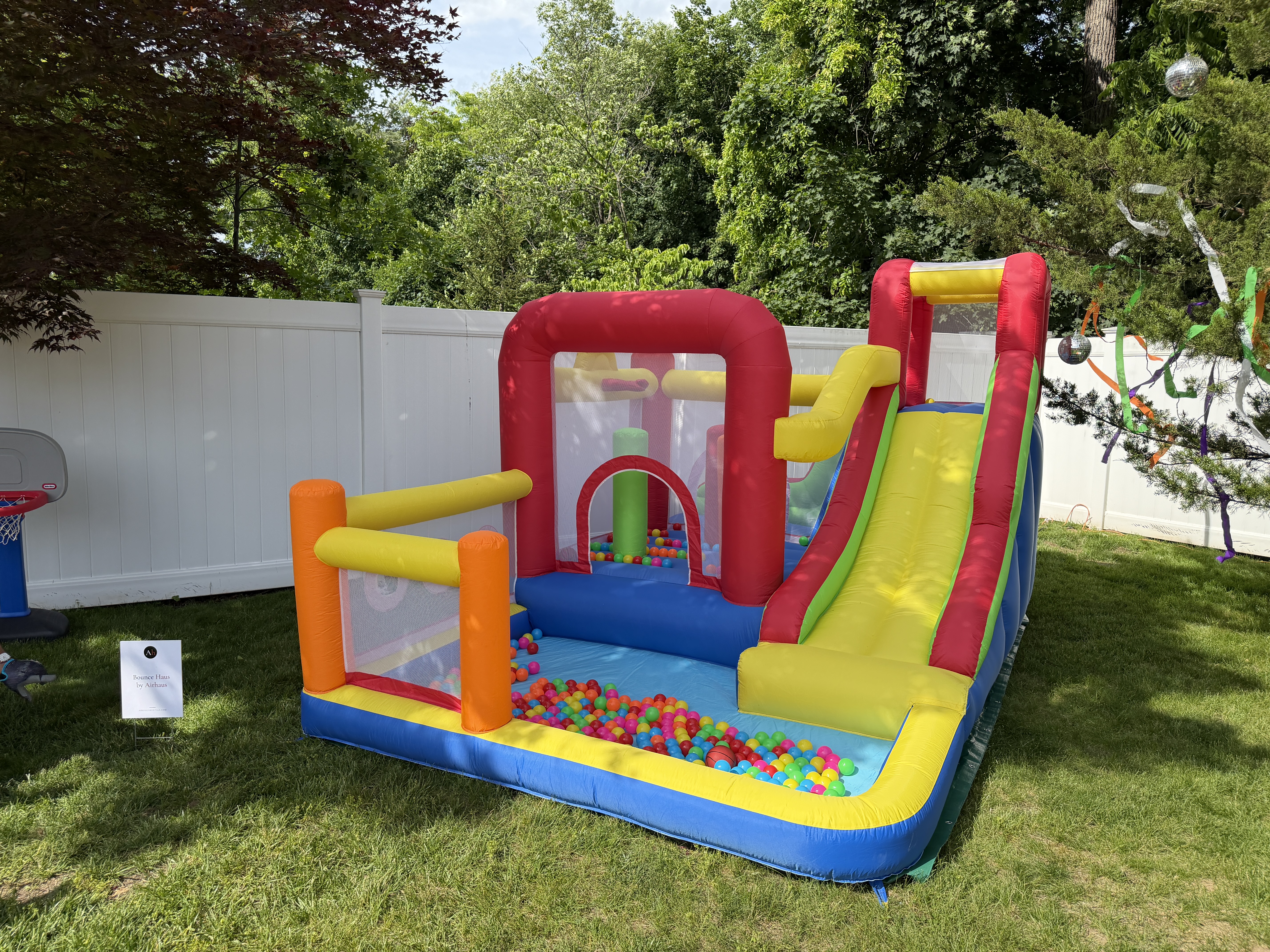 The Play Haus inflatable bounce house with slide, climb wall, and basketball hoops